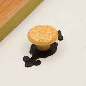 Detail of cream ceramic cabinet knob with floral relief and vintage black metal base
