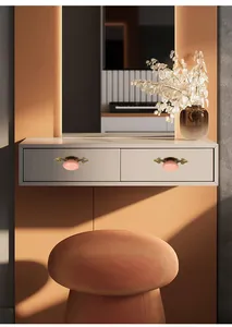 Detail of pink vintage ceramic drawer pulls with ornate bronze bases on a white cabinet
