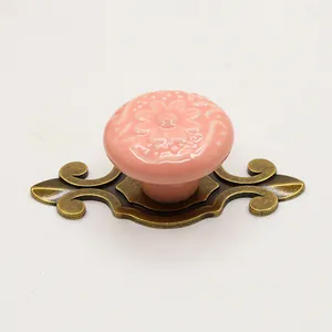 Detail of pink ceramic furniture knob with vintage bronze floral embossed metal backplate