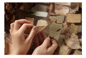 Detail showing hands peeling vintage burnt-edge PET stickers for journaling decor