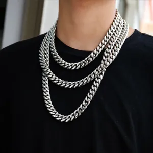 Primo piano di tre catene a maglia cubana in argento indossate su una maglietta nera