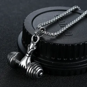 Macro shot of silver dumbbell pendant with muscular hand detail on a box chain