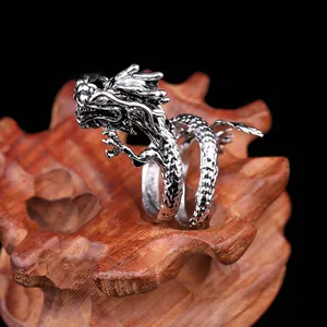 Detalle de anillo de dragón plateado vintage con escamas sobre base de madera