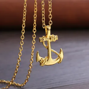 Makroaufnahme einer goldenen Anker-Halskette mit Seildetails auf dunkler Texturoberfläche