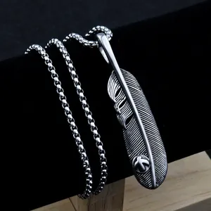 Detail view of vintage stainless steel feather pendant with intricate textures and box chain