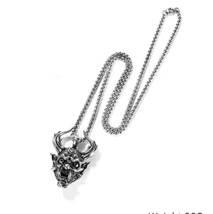 Detailed view of carved Hannya mask pendant on a heavy braided stainless steel chain