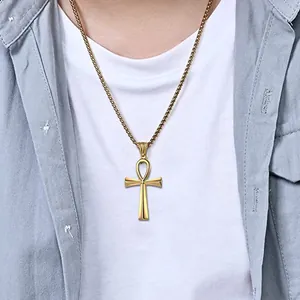 Close-up of polished gold Ankh cross pendant necklace on male model with layered outfit