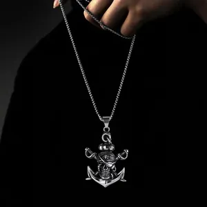 Dettaglio del ciondolo ancora pirata con teschio e spade in acciaio tenuto in mano