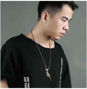 Golden AK-47 assault rifle pendant necklace shown on black streetwear t-shirt detail