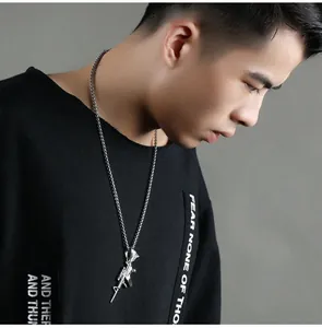Detailed close-up of a silver rifle pendant necklace styled with a black hoodie