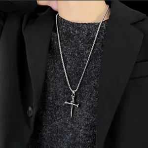 Detailed close-up of a silver gothic cross skull pendant necklace on a male model