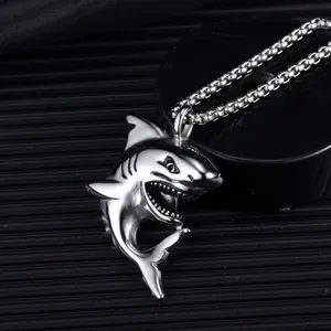 Detailed view of silver shark pendant in polished stainless steel on black box chain