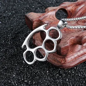 Macro detail of silver knuckle duster pendant with box chain on dark background