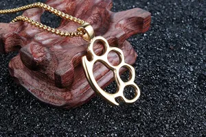 Macro view of gold plated knuckle duster pendant with box chain on wood base