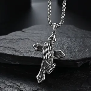Retro stainless steel cross necklace featuring prayer hands on a black rock background