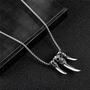 Macro detail of gothic skull and tusk pendant on heavy stainless steel box chain