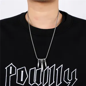 Detailed view of punk skull pendants on a ball chain necklace worn by a model