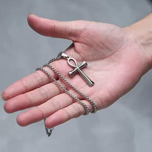 Detailopname van een zilveren Ankh-kruis hanger van roestvrij staal in de hand