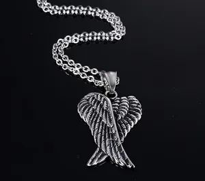 Macro shot of silver angel wing pendant with detailed feather texture on black mirror