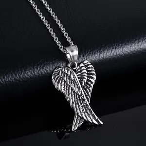 Vintage silver angel wing pendant necklace with detailed feathers on a black leather background