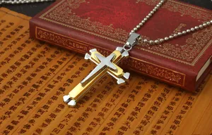 Detalle del colgante de cruz de triple capa en oro y plata sobre una cadena de bolas