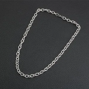 Detail of silver stainless steel cross chain with lobster clasp on leather background
