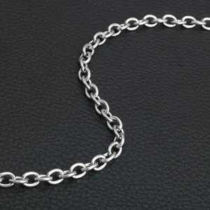 Detailed top view of a silver stainless steel cross chain on a black leather background