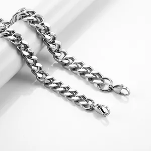 Polished stainless steel Cuban link chains with lobster clasp on minimalist white pedestal