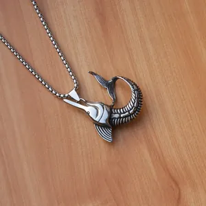 Macro detail of silver marlin fish pendant and box chain on a wood grain background