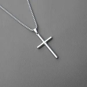 Close-up of polished silver stainless steel cross pendant on a classic box chain