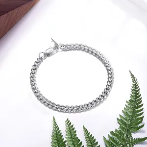 Polished silver Figaro link chain necklace with lobster clasp shown on a white tabletop