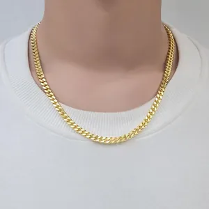 Gros plan d'une grosse chaîne cubaine dorée pour homme portée sur un t-shirt blanc