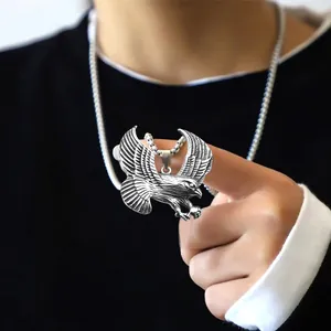 Gedetailleerde close-up van een zilveren arend hanger ketting gedragen door man