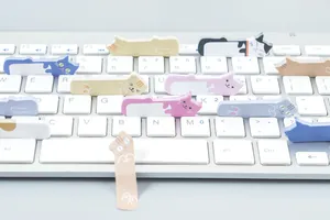 Simpatici post-it a forma di gatto disposti su una tastiera bianca per l'uso in ufficio