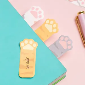 Note adesive e segnalibri a forma di zampa di gatto su taccuino e scrivania rosa