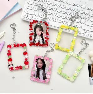 Detail of four acrylic fruit photocard holders with heart-shaped metal keychains on a desk