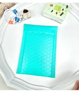 Detail of a turquoise padded bubble mailer inside a white tray with creative decor
