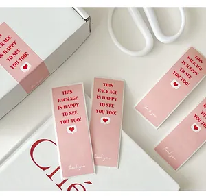 Detail of pink rectangular package sealing sticker with red text and heart accents