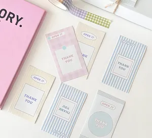 Close-up of pastel plaid and striped Thank You sealing stickers on a white textured desk