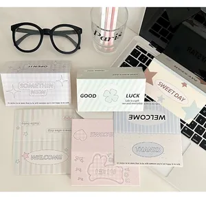 Flat lay of pastel folding card packaging with heart motifs on a desk workspace