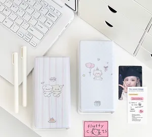 Detailed view of pink and blue cartoon photocard albums on a minimalist white desk