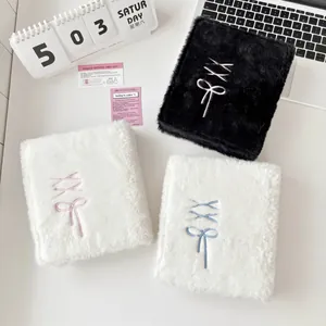 A6 plush binder cover with bow embroidery in black and white styles on desk