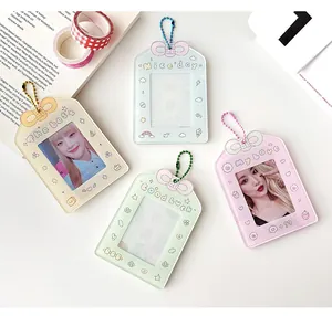 Vista piatta di porta fotocard pastello con ciondoli a fiocco e catenelle in metallo