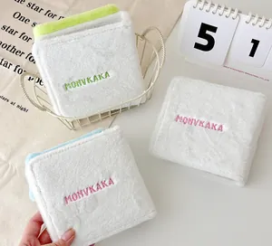 Detailed view of three white plush photocard holders with colorful embroidery and soft texture