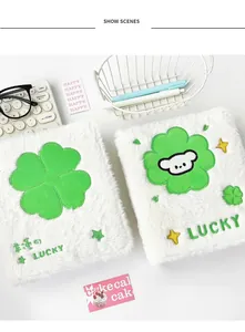 Detail of plush A6 photocard binder with green clover embroidery and soft white faux fur