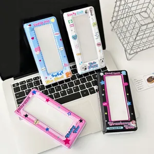 Y2K style cartoon photo card albums in blue, white, pink and black on a laptop keyboard