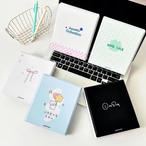 Five assorted mini photo albums with colorful covers displayed around a laptop