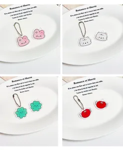 Gros plan de quatre pendentifs en acrylique avec chaînes à billes sur une assiette décorée