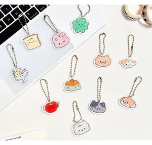 Vue à plat de porte-clés mignons en acrylique avec divers dessins animés sur un bureau