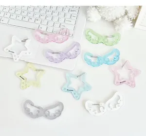 Detalle de colgantes de acrílico con estrellas brillantes y alas de ángel